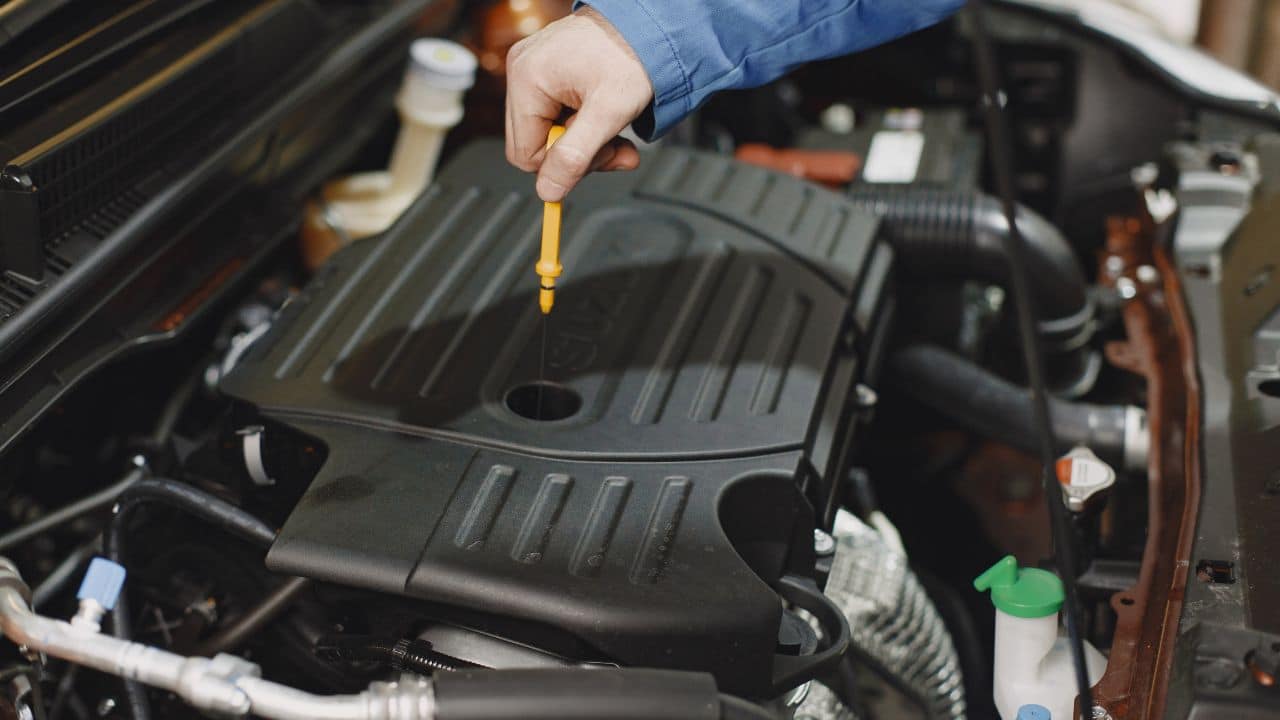 Mechanik kontroluje hladinu motorového oleja v aute počas prípravy na zimnú sezónu.
