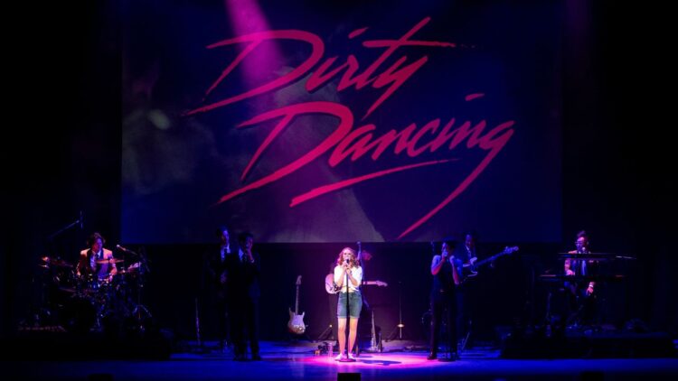 Živá hudobná show Dirty Dancing in Concert s orchestrom a spevákmi na pódiu pod nápisom Dirty Dancing.
