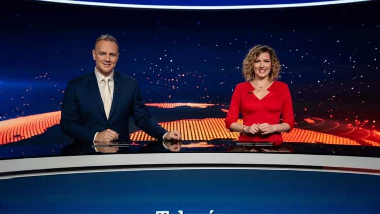 Patrik Švajda a Miriam Kalisová počas vysielania Televíznych novín TV Markíza, sediaci za moderátorským stolom na pozadí spravodajskej grafiky.