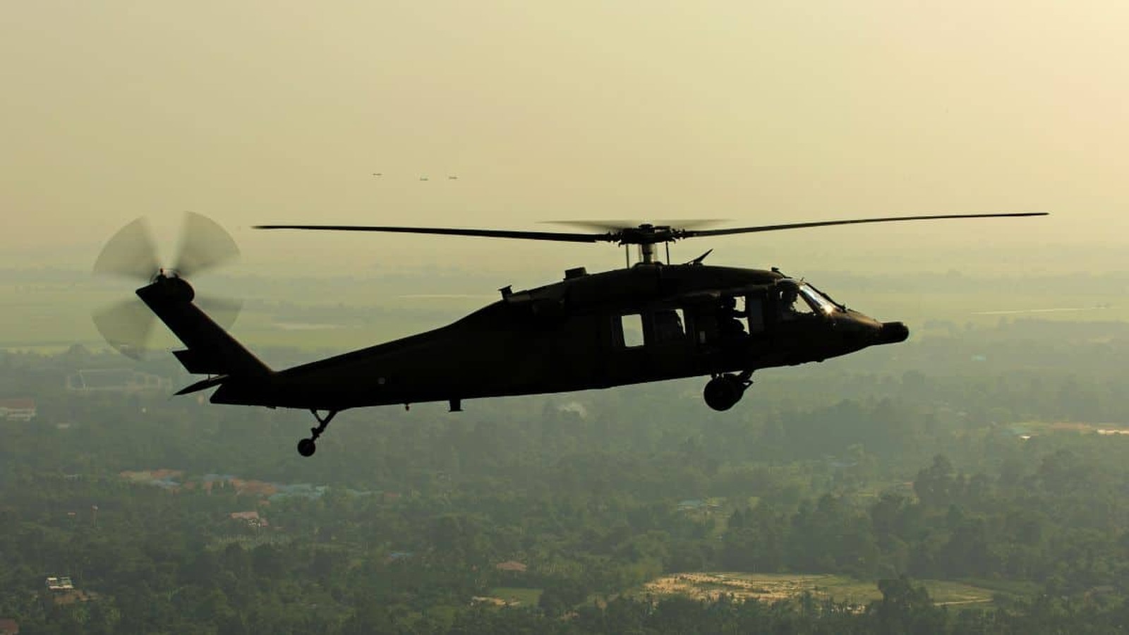 Vojenský vrtuľník UH-60 Blackhawk počas letu nad krajinou v rámci obranných operácií.