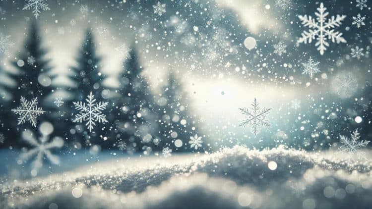 Detailný záber na sneženie so zameraním na snehové vločky, ktoré jemne padajú na zasneženú krajinu, v pozadí sú siluety stromov.