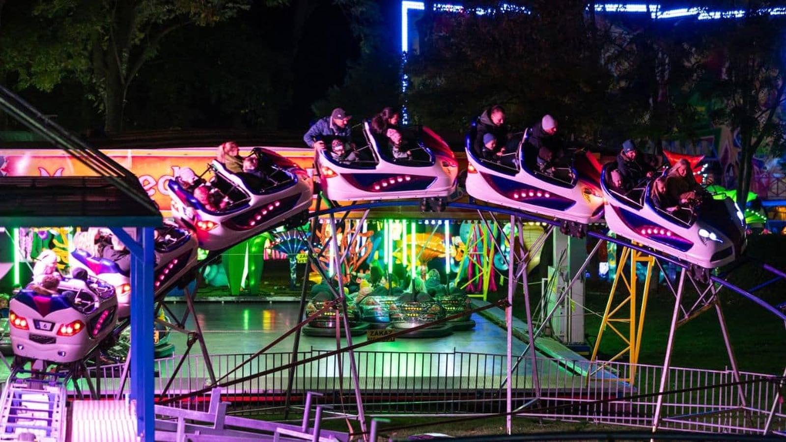 Nočné jazdy na horskej dráhe v zábavnom parku WINTER WONDERLAND, obklopené svetelnou výzdobou a veselými návštevníkmi.