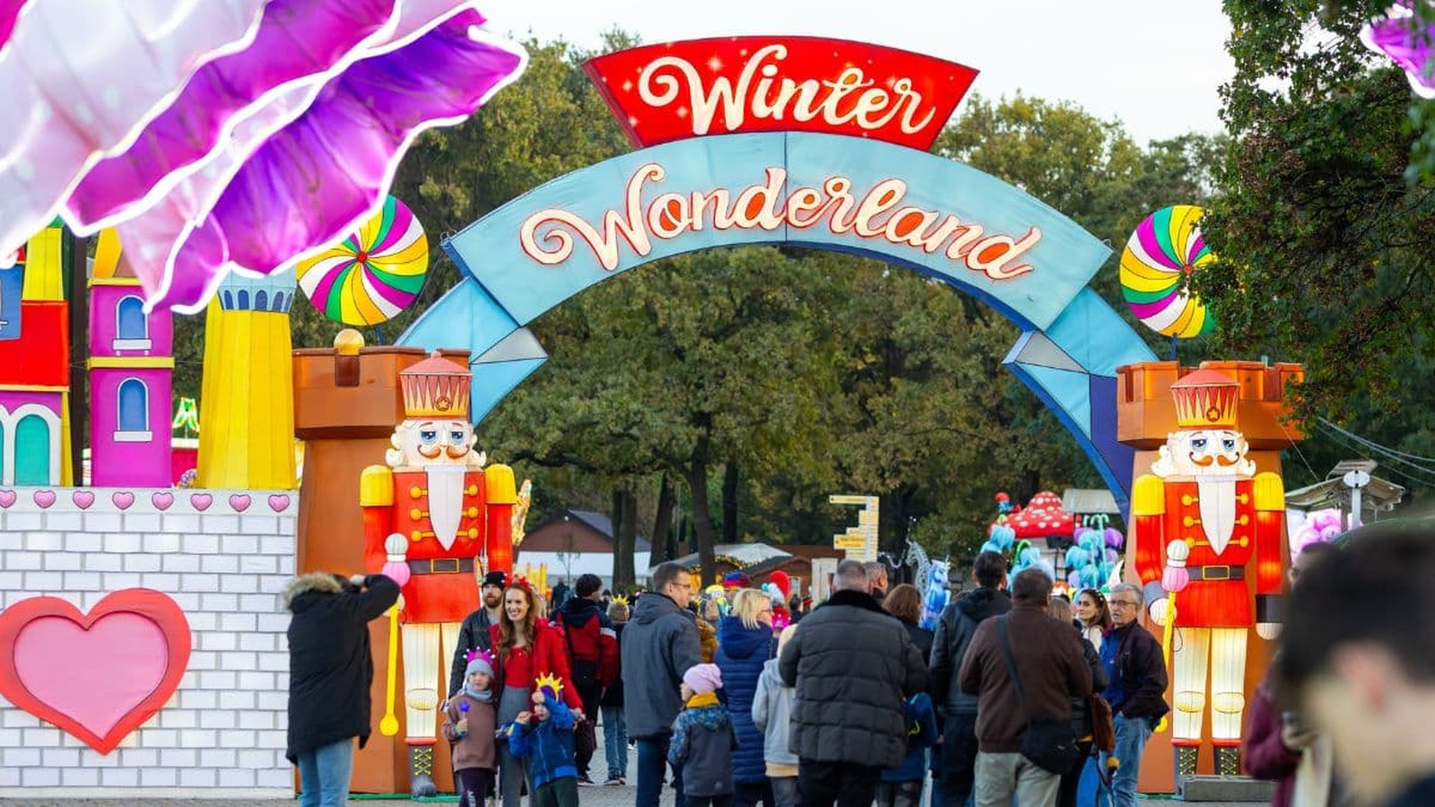 Vstupná brána do zábavného parku WINTER WONDERLAND, obklopená rozprávkovými dekoráciami a postavami luskáčika, s množstvom návštevníkov užívajúcich si zábavu.