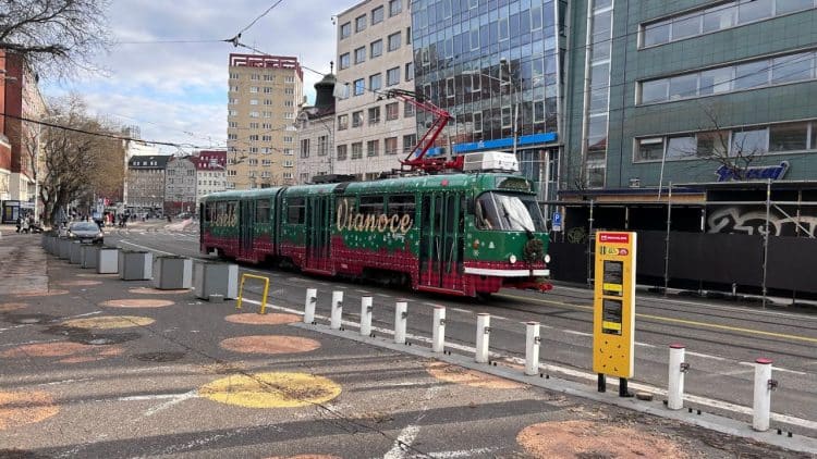 Vianočná električka v Bratislave, vyzdobená sviatočnými motívmi v zeleno-červenej farbe, prechádza centrom mesta počas vianočnej sezóny.