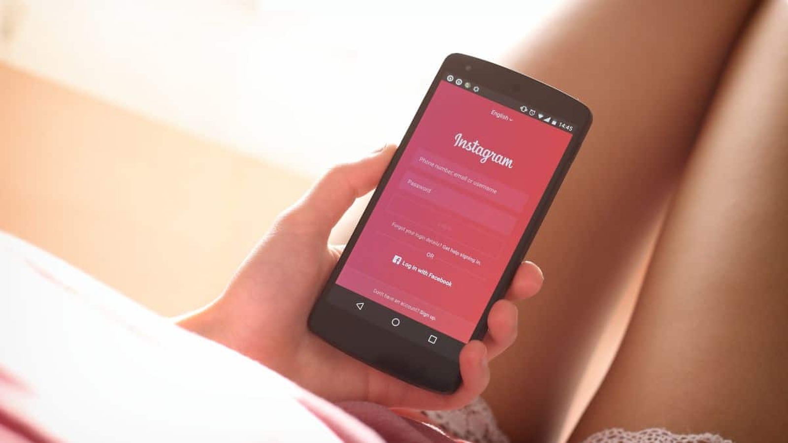 Osoba držiaca smartphone so zobrazenou prihlasovacou obrazovkou Instagramu.