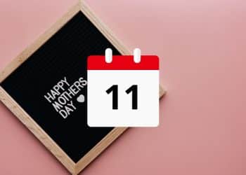 Kalendár s dátumom 11. mája a nápisom "Happy Mother's Day" na čiernej tabuli s dreveným rámom na ružovom pozadí.