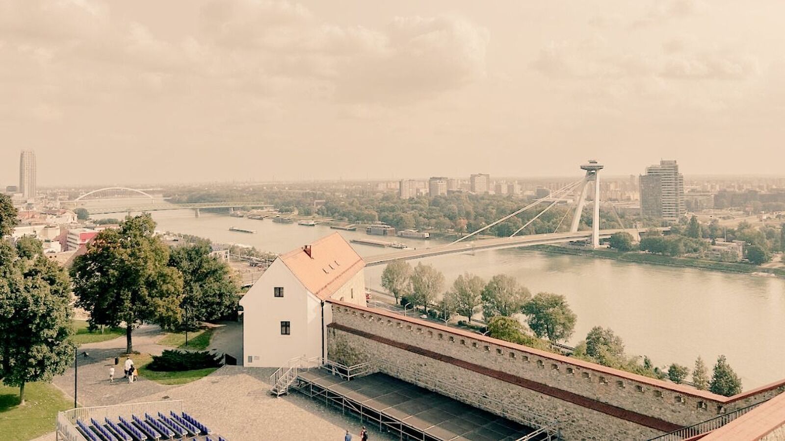 Pohľad z Bratislavského hradu na rieku Dunaj s Mostom SNP a panorámou moderného mesta v historickom tóne.